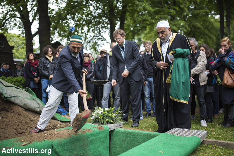 פעילים מתכנסים בבית קברות לטקס קבורה של מהגר בלתי מזוהה מסוריה שמת בים בדרכו לאירופה, ברלין, 19 ביוני, 2015. ההלוויה נוהלה על ידי אימאם כחלק מקמפיין פוליטי שנקרא ״המתים באים״ שאורגן על ידי ״המרכז ליופי פוליטי״, קבוצת אמנים פעילים המבוססת בברלין. פעולה זו היא אחת מכמה פעולות לערור מודעות המאורגנות על ידי הקבוצה. (אן פאק/אקטיבסטילס)