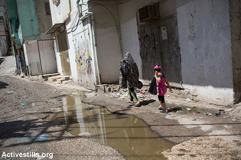 ילדות חוצות רחוב מוצף ביוב במחנה הפליטים שועפת, מזרח ירושלים, 2 ביוני 2015. (יותם רונן/אקטיבסטילס)