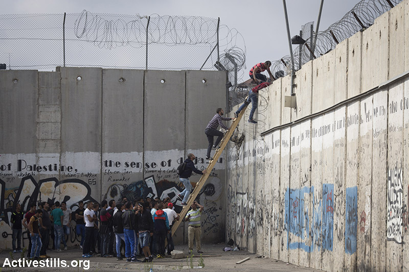 פלסטינים מטפסים על חומת ההפרדה בעיירה אל-ראם, ליד מחסום קלנדיה בין רמאללה וירושלים, על מנת להשתתף בתפילות יום השישי במסגד אל-אקצא, ביום שישי השני של חודש הרמדאן , 26 ביוני, 2015. קרא/י עוד. (אורן זיו/אקטיבסטילס) 