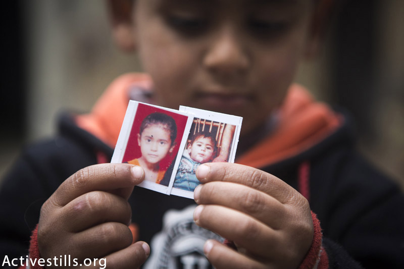 פאדי איבראהים אבו-׳וסא (4) מחזיק תמונות שני אחיו, שיהאג (9) ומוחמד (2) אשר נהרגו במתקפה ישראלית יחד עם שני הוריו ו-4 בני משפחה נוספים, זאוואדאה, רצועת עזה, פברואר 24, 2015. (אן פאק / אקטיבסטילס)