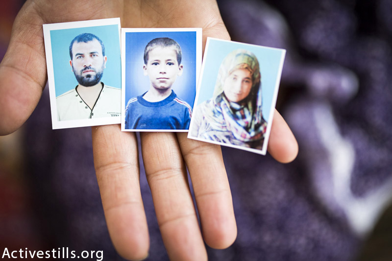 תמונות של ראדאד אחמד טנבורה (36), ושני ילדיו, אחמד (15) ואמה (13), מוחזקים בידיו אשתו אליז׳בת במה שנשאר מדירתם בית להיה, רצועת עזה, 19 למרץ, 2014. אליזבת נפצעה בהתקפה. (אן פאק / אקטיבסטילס)