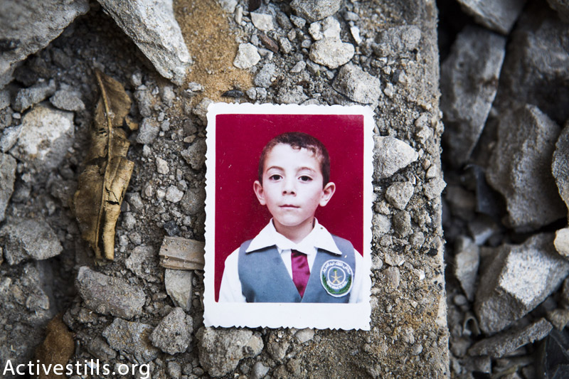 תמונה של עבדאללה אבדל האדי אל-מג׳דלאווי (13) מצולמת על חורבות ביתו, בו נהרג יחד עם שני אחדיו ושני בן דודים בהתקפה ישראלית, ג׳אבליה, רצועת עזה, 19 מרץ, 2015. (אן פאק / אקטיבסטילס)
