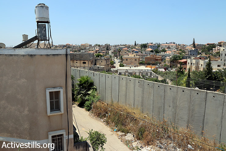 חומת ההפרדה עוברת בין בתי בכפר נזלת עיסא (מימין) אשר בגדה המערבית והעיר באקה אל-גרבייה הנמצאת בתוך הקו הירוק (מהשמאל), 17 ביולי 2015. (אחמד אל באז/אקטיבסטילס)
