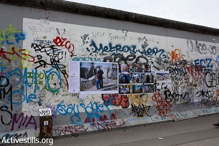 תערוכת הרחוב "משפחות שנמחקו (#ObliteratedFamilies) של קולקטיב אקטיבסטילס תלוייה ב״East Side Gallery״ על חומת ברלין ההרוסה, ברלין, גרמניה, 12 ביולי 2015. תערוכת הרחוב היא חלק מקמפיין המציין שנה להתקפה הישראלית בעזה ומציגה תמונות של משפחות שניספו במהלכה. (אן פאק/אקטיבסטילס)