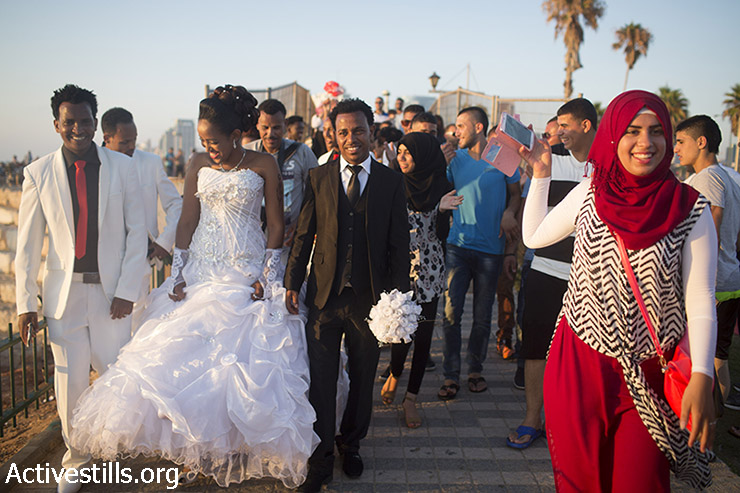 צעירה פלסטינית מצלמת עם הטלפון הסלולרי שלה מבקשי מקלט מאריתריאה ביום חתונתם בחוף יפו, במהלך היום השני של חג עיד אל-פיטר, 18 ביולי 2015. (אורן זיו/אקטיבסטילס)