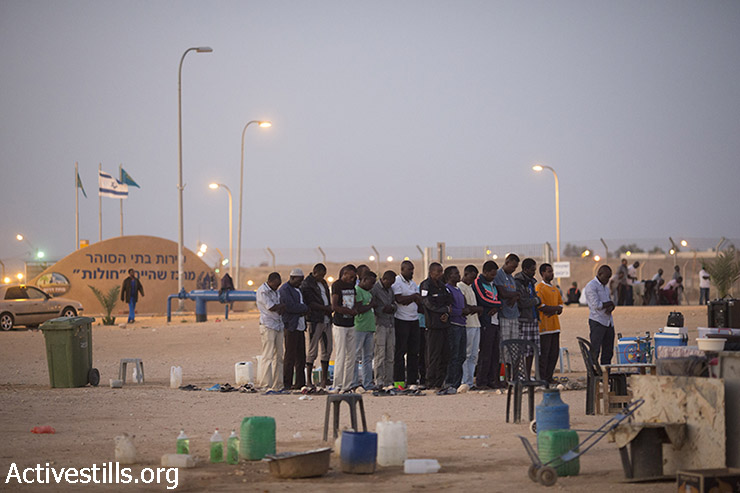 מבקשי מקלט אפריקאים הכלואים בבית המעצר חולות מתפללים לאחר אכילת ארוחת האיפטאר, ארוחה מסורתית לשבירת הצום בחודש המוסלמי הקדוש של הרמדאן, נגב, 5 ביולי 2015. (אורן זיו/אקטיבסטילס)