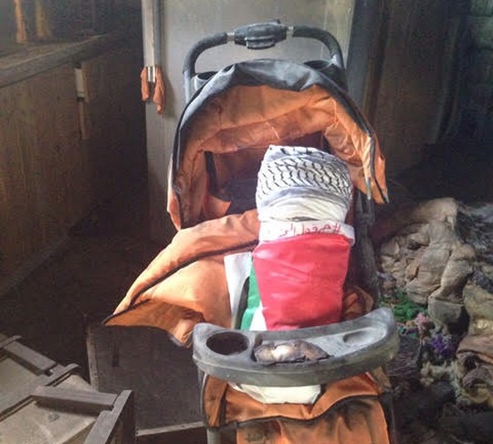 עגלה ובה בובת תינוק עטופה בדגל, בבית משפחת דוואבשה השרוף (סמאח סלאימה)