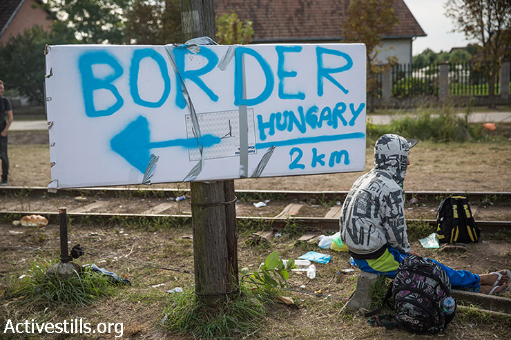 פליט נח ליד שלט המציין את הכיוון לגבול הונגרי בסמוך לגבול סרביה-הונגריה, 15 בספטמבר, 2015. ב -15 בספטמבר, לאחר שפליטים רבים חצו את הונגריה במסעם למערב וצפון אירופה, הונגריה סגרה את גבולה ולא איפשרה לפליטים להיכנס לתחומה. (יותם רונן/אקטיבסטילס) 