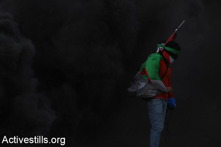 נער פלסטיני עומד מוקף בגז מדמיע שנורה ע"י הצבא במהלך עימותים עם סטודנטים מאוניברסיטאות פלסטיניות מחוץ למתחם הכלא הצבאי עופר, בסמוך לעיירה ביתוניא בגדה המערבית, 3 נובמבר 2015. (אקטיבסטילס)