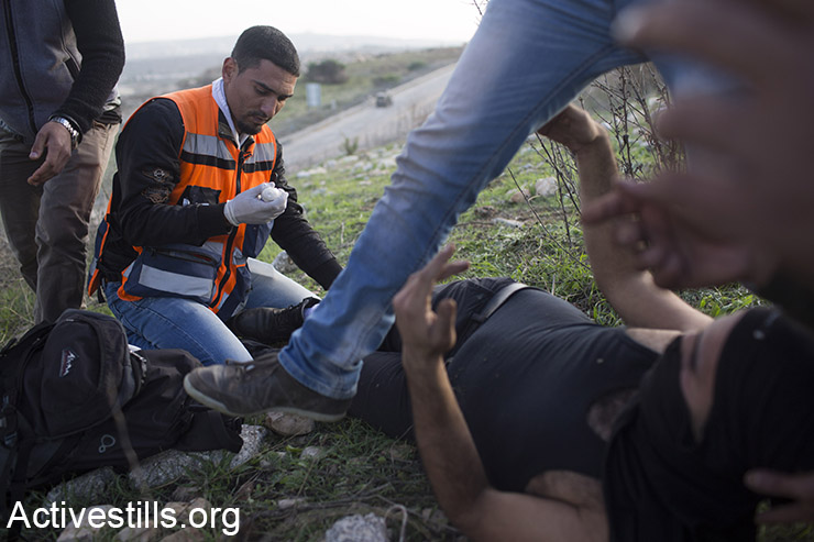 חובשים מטפלים בנער פלסטיני שנפצע מאש חיה, שנורתה על ידי הצבא הישראלי, במהלך עימותים מחוץ הכלא הצבאי עופר, סמוך לעיירה ביתוניא, 27 נובמבר 2015. (אקטיבסטילס)