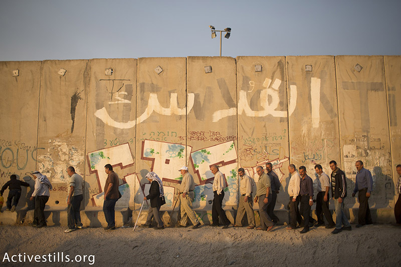 פלסטינים צועדים ליד חומת ההפרדה הישראלית ליד מחסום קלנדיה, המפריד בין העיר רמאללה וירושלים, בדרכם להתפלל במסגדר אל-אקסה, רמאדאן, 26 יוני, 2015. יותם רונן / אקטיבסטילס