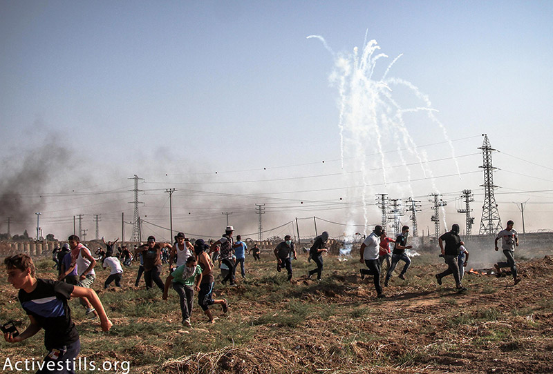 צעירים פלסטינים רצים מגז מדמיע שנורה על ידי הצבא הישראלי מהצד השני של הגבול באזור נחל עוז, רצועת עזה, 16 אוקטובר, 2015. עז זאנון / אקטיבסטילס