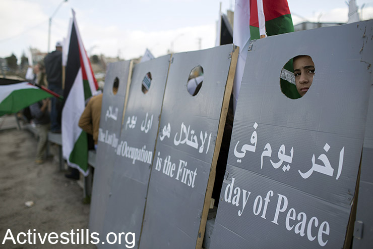 פעילים מחזיקים חלקים המדמים את חומת ההפרדה, במהלך הפגנה נגד הכיבוש, על הכביש הראשי המחבר בין ירושלים וחברון, סמוך לבית ג'אלה, הגדה המערבית, 15 ינואר 2016. (אקטיבסטילס)