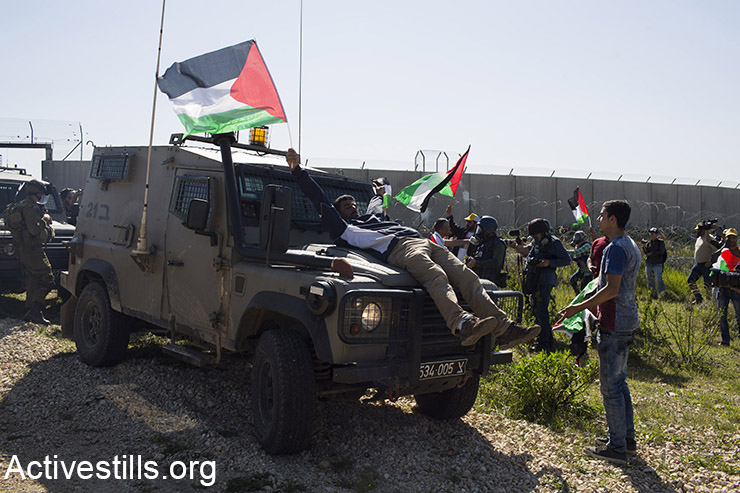 מפגין נשכב על גבי ג'יפ צה"ל ומניף דגל פלסטין במהלך הפגנה לציון 11 שנים למאבק נגד הגדר בכפר בילעין בגדה המערבית, סמוך לרמאללה, 19 בפברואר, 2016. (אורן זיו / אקטיבסטילס)