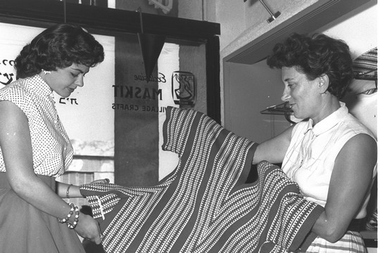 רות דיין מציגה רקמה תימנית למלכת היופי של ישראל, שרה טל, בחנות של "משכית"בתל אביב, 1956 (הנס חיים פין, אוסף התצלומים הלאומי)
