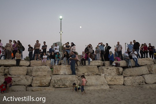 משפחות פלסטיניות צופות בשקיעה בחוף הים מצפון ליפו. בעוד רגע יפקע תוקף האישורים שחילקה ישראל והם ישובו לבתיהם בגדה המערבית. 14 בספטמבר 2016. (אורן זיו/אקטיבסטילס). 