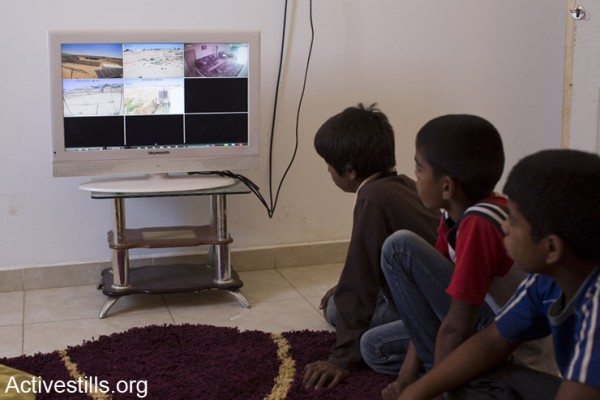 ילדים ממשפחת עדיסאן צופים בהקלטה של מצלמות האבטחה המותקנות בחצר בית המשפחה, המתעדות את חלוקת צווי ההריסה (אקטיבסטילס)