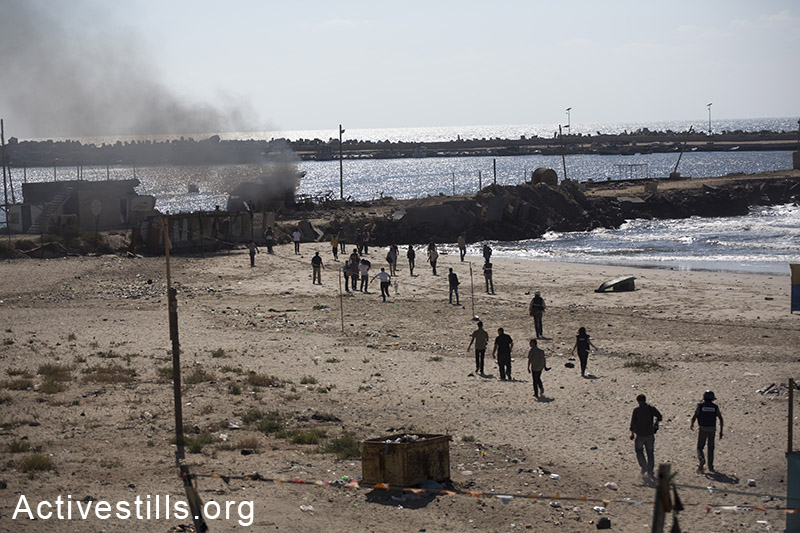 פלסטינים רצים לחלץ ארבעה ילדים שנהרגו מירי הצבא על אזור נמל עזה. הילדים, בני אותה משפחה, בחוף ונורו בפגיעה ישירה. ה-16 ליולי, 2014. (אן פאק/אקטיבסטילס)