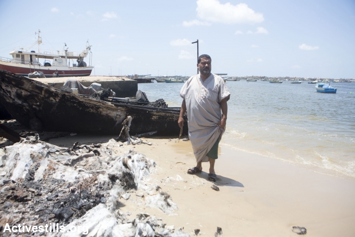 דייג עומד ליד סירה שהופצצה בנמל בעזה (צילום: אן פאק / אקטיבסטילס)