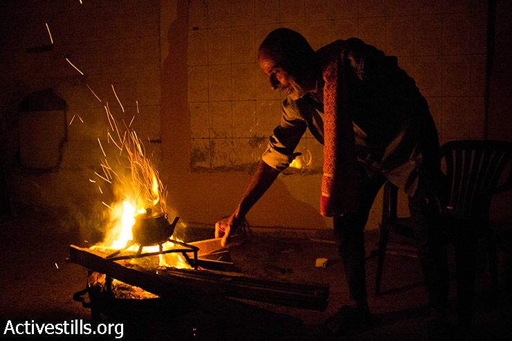אבו עלא מכין תה על האש למשפחתו. בעקבות ההפצצות הבית נותק מחשמל ומגז. 11 באוגוסט 2014. (באסל יאזורי/אקטיבסטילס)