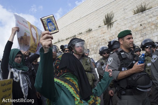 אשה פלסטינית מניפה ספר קוראן מול שוטרים (אקטיבסטילס)