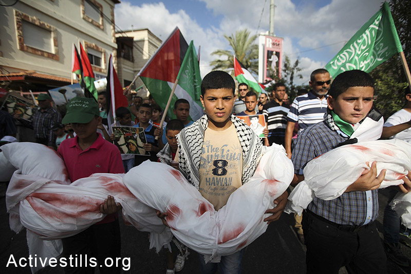 ילדים פלסטינים תושבי ישראל אוחזים בבובות עטופות בתחריכים ומוכתמות בצבע אדום במהלך הפגנה נגד המלחמה בעזה. תמרה, 2 באוגוסט, 2014. (פיאז אבו רמלה/אקטיבסטילס)
