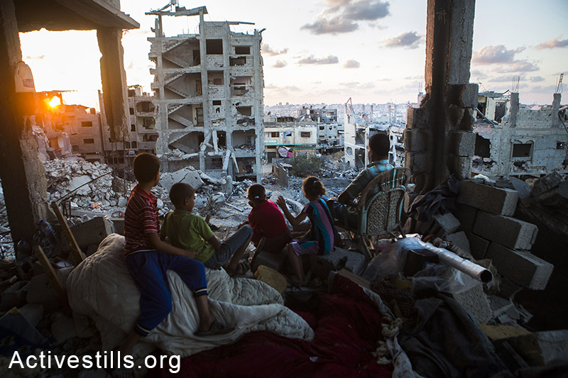 משפחה פלסטינית יושבת בביתה שהופצץ ע״י הצבא ברובע תופח בעזה, 21 בספטמבר, 2014. (אן פק/אקטיבסטילס) 