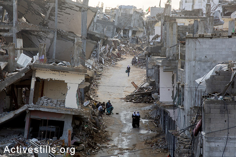 תלמידות פלסטיניות הולכות ברחוב מוצף מי גשמים בשכונת סג'עייה ההרוסה בעזה, 4 בנובמבר, 2014. שבעת שבועות הלחימה בין ישראל לעזה הותירו מעל ל-108,000 פלסטינים מחוסרי בית. כ- 18,000 בתים נהרסו כליל או חלקית בעזה בעקבות הפצצות הצבא. (אן פאק/אקטיבסטילס)