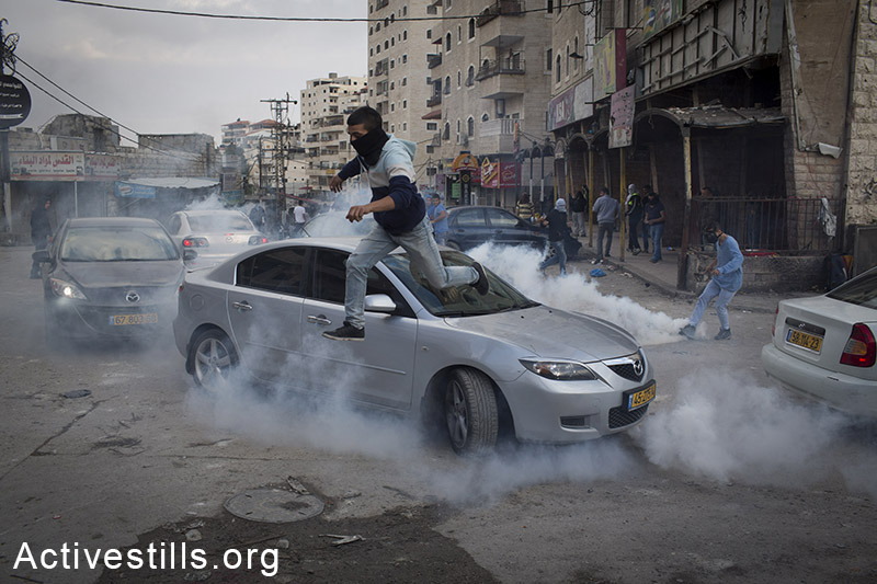 צעיר פלסטינים רץ מגז מדמיע שנורה על ידי שוטרים במהלך הפגנה במחנה הפליטים שועפט, מזרח ירושלים, 5 לנובמבר, 2014. (אורן זיו/אקטיבסטילס)