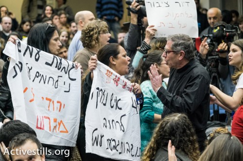תושבות גבעת עמל מניפות באנרים בכנס. (צילום: יותם רונן/אקטיבסטילס)