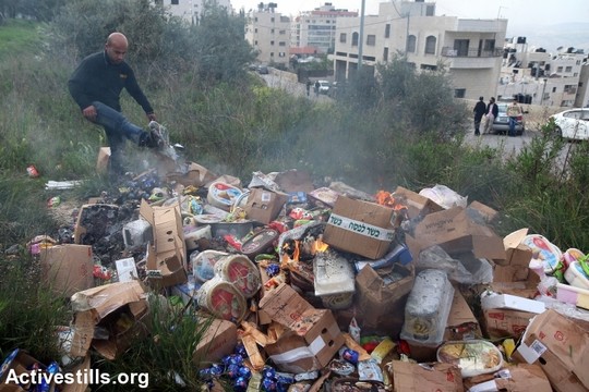 פעילים פלסטינים משמידים מוצרים של חברות ישראליות במהלך קמפיין חרם על חברות מזון ישראליות (אחמד אל-באז/אקטיבסטילס)