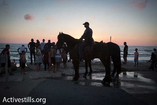 פרש משטרתי בחוף לצד משפחות שחוגגות את עיד אל פיטר (אורן זיו / אקטיבסטילס)