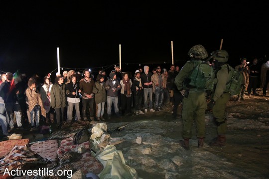 הפעילים יוצרים חומה אנושית מול חיילים שהגיעו כדי לפנות את המחנה. "צומוד, מחנה החירות". הכפר סארורה הגדה המערבית, 20 במאי 2017 (צילום: אחמד אל-באז אקטיבסטילס)