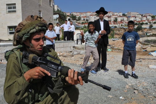 נבוכים מול המיליטריזם הישראלי. ילדים חרדים מול חייל בהתנחלות החרדית ביתר עילית (צילום: נתי שוחט, פלאש90)