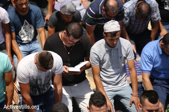 מאמין נוצרי מתפלל בין מאמינים מוסלמים. המחאה איחדה את המזרח ירושלמים. (צילום: פאיז אבו רמלה/אקטיבסטילס)