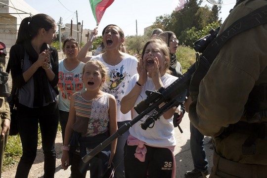 ילדות ונשים פלסטיניות, בהן עאהד תמימי, עומדות מול החיילים במהלך ההפגנה השבועית בנבי סאלח. אפריל 2012 (אקטיבסטילס)