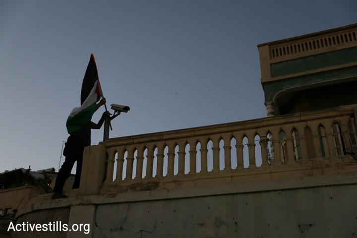 מפגין תולה דגל פלסטין על בית הדין הצבאי, "הבית הירוק" ביפו, במהלך משמרת מחאה בעקבות הטבח במפגינים בגבול עזה. 1 באפריל 2018 (אורן זיו / אקטיבסטילס)