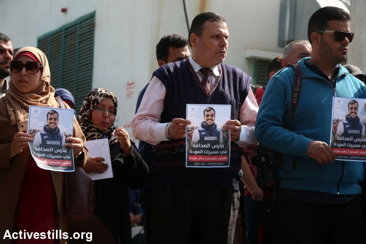 עיתונאים, חבריו של יאסר מורתג'א, נושאים את תמונתו במהלך מסע הלוויתו של הצלם שנהרג מאש חיילים במהלך צעדת השיבה. עזה, 7 באפריל 2018. (מוחמד זאנון / אקטיבסטילס)