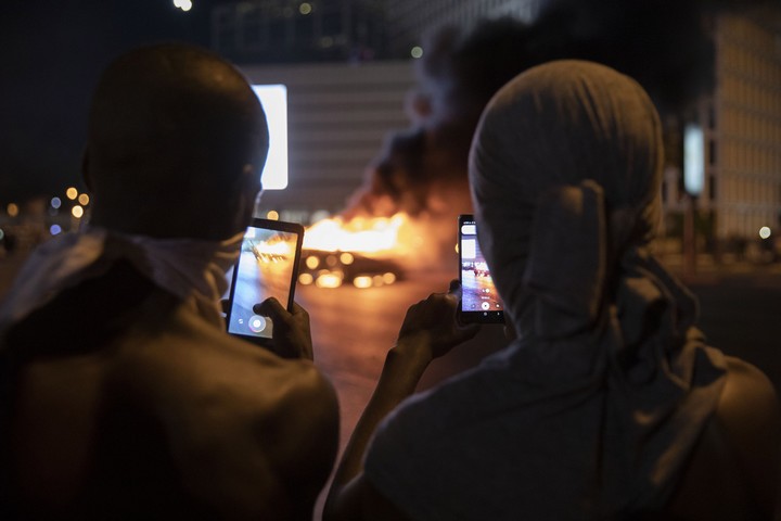 נערים מצלמים מכונית שהוצתה בצומת עזריאלי במהלך המחאה נגד אלימות משטרתית, בעקבות הריגתו של סלמון טקה בידי שוטר. 2 ביולי 2019 (אורן זיו)