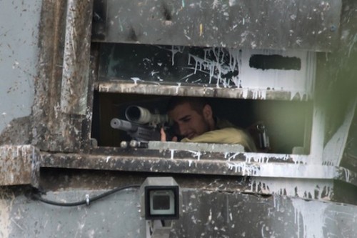 חייל ישראלי מכוון נשק מסוג רוגר מבעד לחומת ההפרדה במהלך עימותים עם צעירים פלסטינים בבית לחם. 11 במרץ 2014. (ראין רודריק ביילר/אקטיבסטילס)