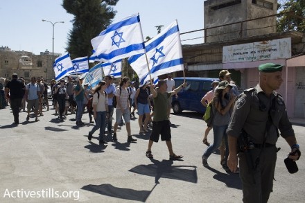 מתנחלים עם דגלים צועדים בתוך סיור שוברים שתיקה בחברון (אורן זיו / אקטיבסטילס)