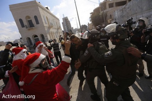 שוטרי מג"ב דוחפים מפגינים מחופשים לסנטה קלאוס. בית לחם (מוסטפא בדר / אקטיבסטילס)
