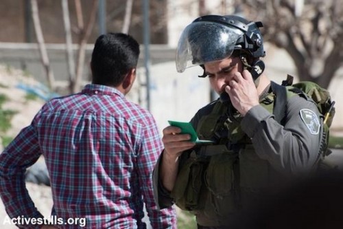 חייל בודק תעודת זהות של פלסטיני. ישראל שולטת ברישום האוכלוסין הפלסטיני ומנפיקה לפלסטינים את תעודות הזהות הירוקות שלהם שמובחנות מאלו התכולות של הישראלים (אקטיבסטילס)