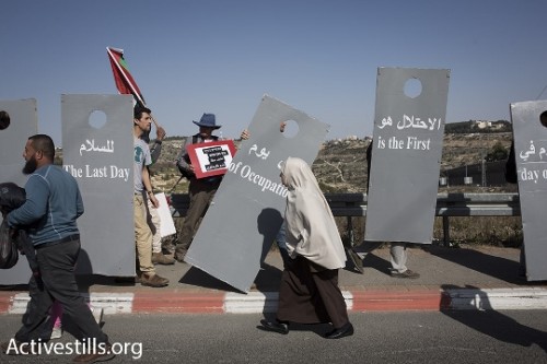 אישה פלסטינית חולפת ליד מיצג חומה בהפגנה במחסום המנהרות (אורן זיו / אקטיבסטילס)