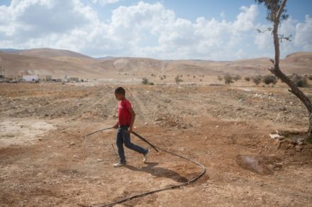 ילד עם צינור מים באזור פסאיל, בקעת הירדן (מרים אלסטר / פלאש90)