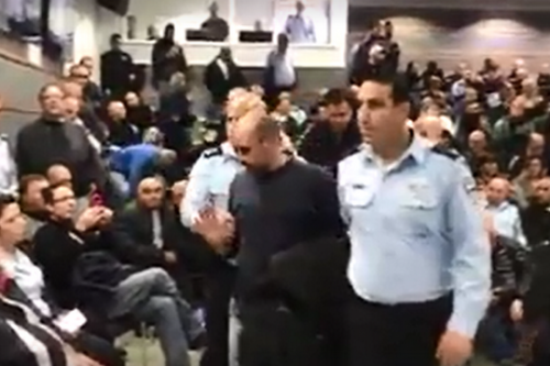יגאל רמג"ם מפונה מהאירוע לחנוכת תחנתהמשטרה ביפו לאחר שצעק לעבר השר ארדן (צילום מסך מסרטון של רוטר.נט)