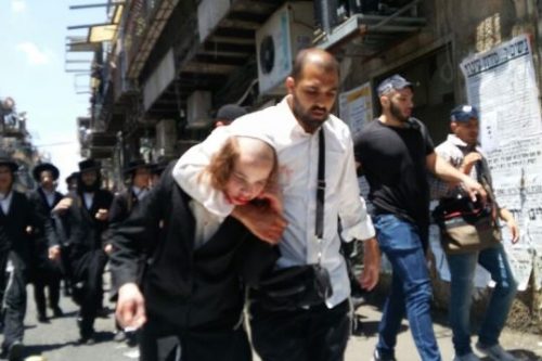שוטר סמוי גורר ילד שנפצע ממכות השוטרים ברחובות "מאה שערים" (צילום: "מחאת החרדים הקיצוניים")