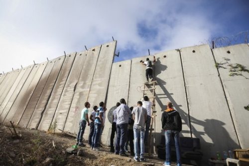 מערכת החינוך משתתפת בבניה של אותן חומות שקיימות במציאות. פלסטינים מנסים לחצות את חומת ההפרדה ליד מחסום קלנדיה (פלאש 90)