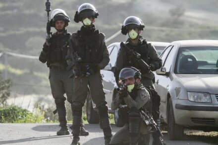 שוטרים לובשים מסכות נגד הקורונה במהלך התנגשויות עם מפגינים פלסטינים בג'בל אל ערמה, ב-11 במרץ 2020 (צילום: נאסר אישתאיה / פלאש 90)