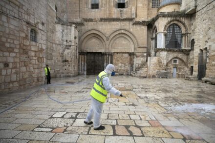 עובד מחטא את החצר הקדמית של כנסיית הקבר הסגורה בירושלים, ב-30 במרץ 2020 (צילום: אוליבייה פיטוסי / פלאש90)